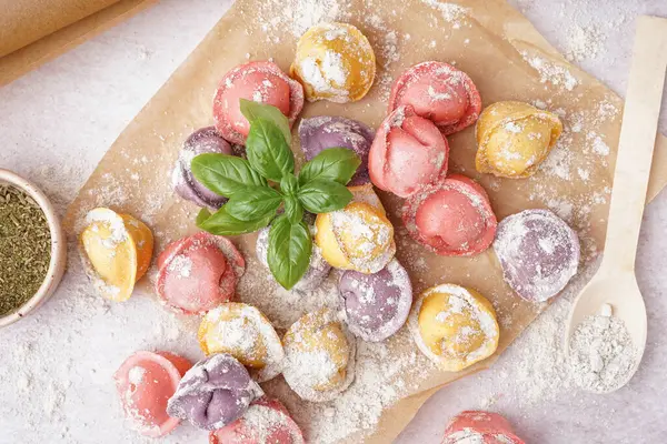 Renkli çiğ hamur köfteleri ve beyaz arka planda fesleğenli fırın kağıdı.