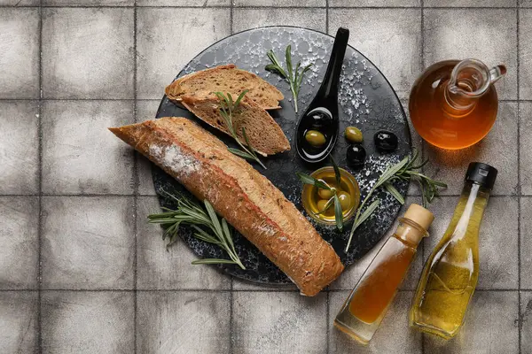 Şişeler, sürahi ve bir kase taze zeytinyağı ve gri fayanslı ekmek.