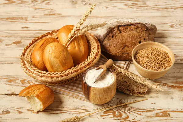 Buğday dikenli somunlar ve beyaz ahşap zemin üzerinde un.