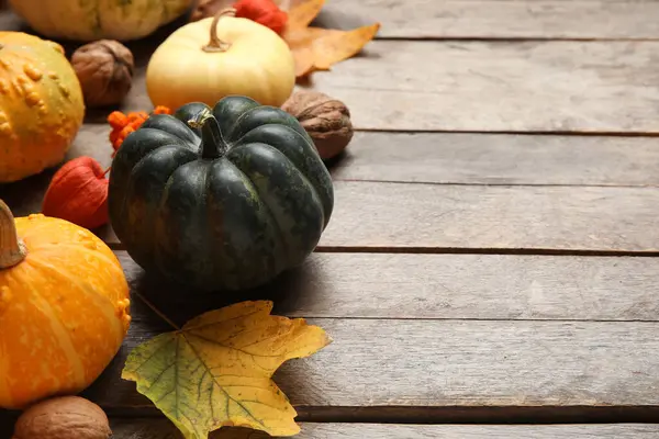 Kahverengi ahşap arka planda balkabağı ve sonbahar yapraklarıyla kompozisyon