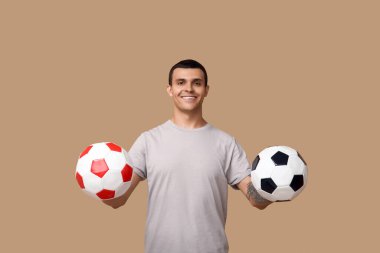 Kahverengi arka planda futbol topları olan yakışıklı bir genç.