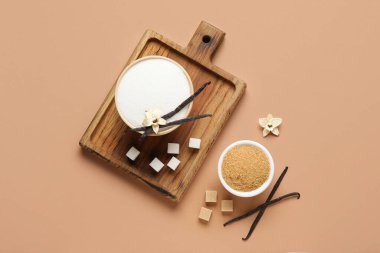 Kahverengi arka planda aromatik vanilya şekeri, çiçekler ve sopalarla dolu kaseler