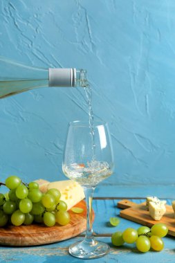 Beyaz şarap, cam ve tahtalara dökülüyor mavi ahşap masada üzümlü.