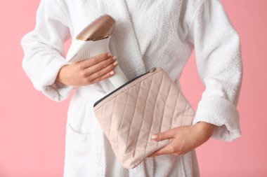 Kozmetik çantalı ve pembe arka planda modern fotoğraf makinesi olan güzel bir kadın.