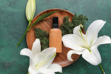 Kozmetik ürün şişesi, yosun ve yeşil arka planda güzel zambak çiçekleri olan kompozisyon