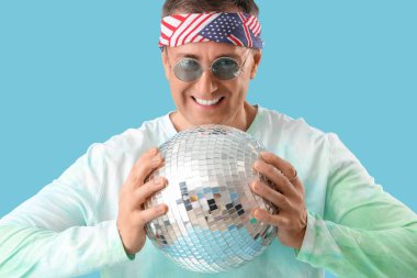 Mavi arka planda disko topu olan havalı olgun bir adam, yakın plan.