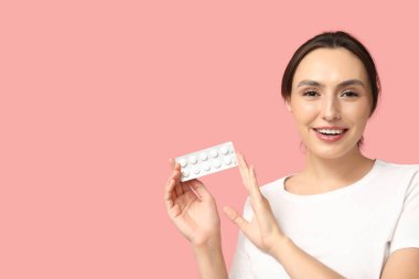 Pembe arka planda hapları olan güzel bir kadın.