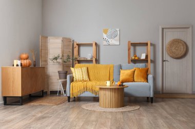 Kahve masasında gri kanepe ve balkabağı olan modern oturma odasının içinde.