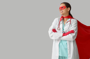 Beyaz arka planda süper kahraman kostümlü genç bayan doktor.