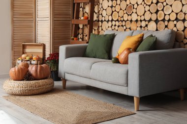 Gri kanepe, hasır puf ve balkabağı olan rahat bir oturma odası.