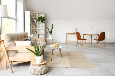 Konforlu kanepe ve beyaz mobilyalarla aydınlık oturma odasının içinde.