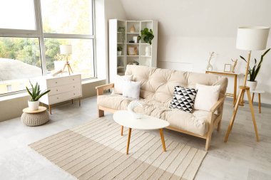 Konforlu kanepe ve beyaz mobilyalarla aydınlık oturma odasının içinde.