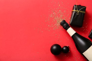 Bir şişe şampanya ve kırmızı arka planda hediye paketi.