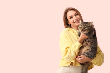 Pembe arka planda sevimli tekir kedisi olan güzel genç bir kadın.