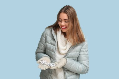 Mavi arka planda dekoratif kar taneleri olan güzel genç bir kadın.