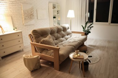 Akşamları beyaz kanepe ve parlayan lambayla modern oturma odasının içinde.