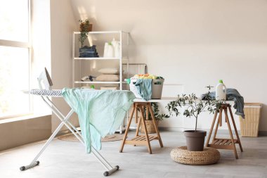 Çamaşır odasındaki ütü masasında elektrikli ütü ve buruşuk gömlek.