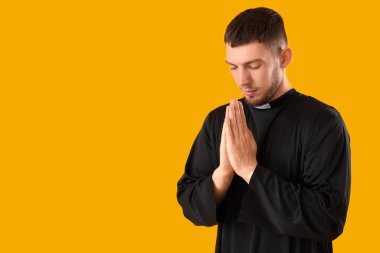 Genç rahip sarı arka planda dua ediyor.