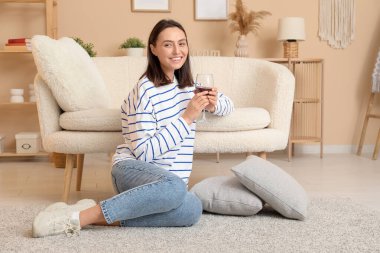 Bir kadeh şarapla evde oturan güzel bir kadın.