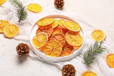 Beyaz arka planda kurumuş portakal dilimleri, kozalaklı ve köknar dalları.