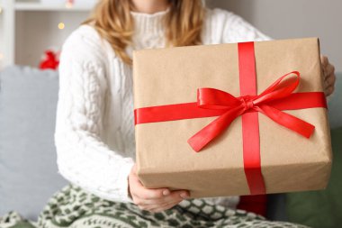 Evde Noel hediyesi kutusu olan genç bir kadın, yakın plan.