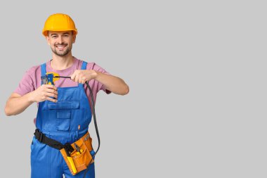 Gri arka planda tel ve kıvrımlı erkek elektrikçinin portresi