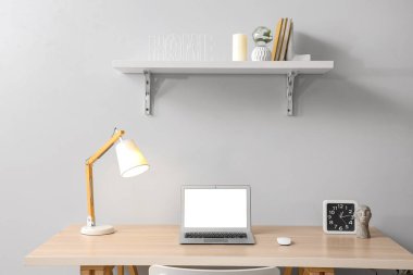 Parlayan lamba ve ışık duvarının yanında modern dizüstü bilgisayarı olan şık bir iş yeri.