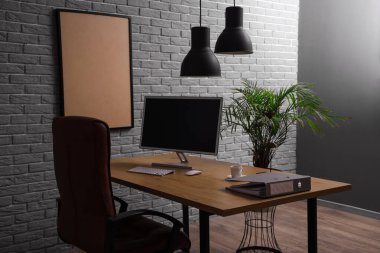 Tuğla duvarın yanında rahat koltuğu olan şık bir iş yeri.