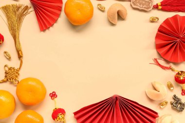 Frame made of fortune cookies with mandarins and Chinese symbols on beige background. New Year celebration