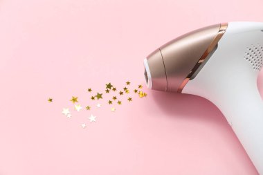 Modern fotoğraf makinesi ve pembe arka planda altın pullar.