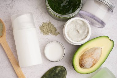 Taze avokado ve hafif arkaplanda kozmetik ürünler içeren kompozisyon