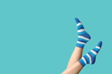 Mavi arka planda çizgili çoraplı genç kadın bacakları