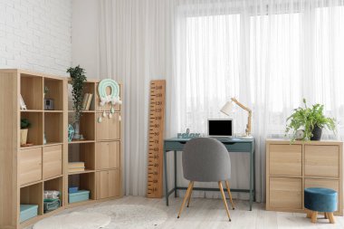 Rahat çalışma alanı, dizüstü bilgisayarı ve ahşap stadyumu olan modern çocuk odası.