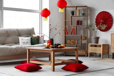 Mandalinalı kahve masası, çay seti ve şenlikli oturma odasında yerde yastıklar. Çin Yeni Yıl Kutlaması