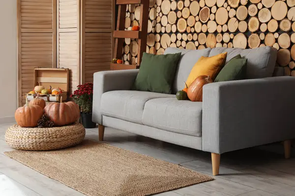 Gri kanepe, hasır puf ve balkabağı olan rahat bir oturma odası.