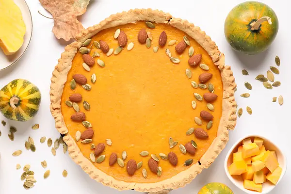 Bademli balkabaklı tart ve beyaz arka planda tohumlar.