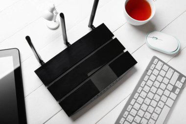 Beyaz ahşap arka planda klavyesi ve kulaklığı olan modern wi-fi yönlendirici