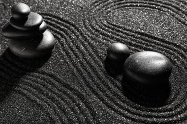 Japon kaya bahçesinde çizgileri olan koyu kumdaki taşlar. Zen kavramı