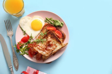 Lezzetli kızarmış yumurta, tost, domates, roka, bir bardak meyve suyu ve mavi arka planda hediye paketi.