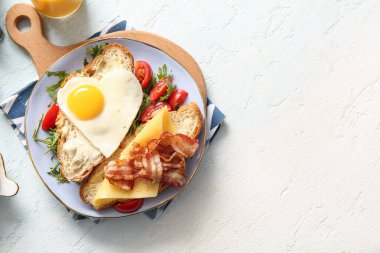 Lezzetli kızarmış yumurta, kruvasan, pastırma, domates ve roka.