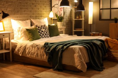 Rahat yatağın üzerinde battaniyeler ve gece lambaları olan modern yatak odasının içi.