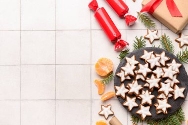 Lezzetli yıldızlar Noel kurabiyelerini köknar dalları, mandalinalar ve beyaz karo arka planda hediyelerle şekillendirdiler.