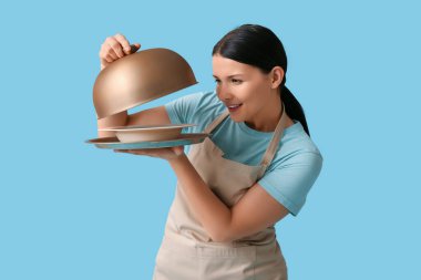 Mavi arka planda tepsisi ve saati olan güzel bir garson kız.