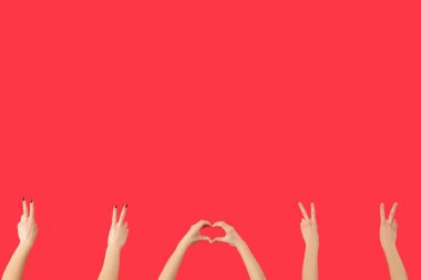 Kırmızı arka planda barış ve kalp hareketlerini gösteren kadın elleri