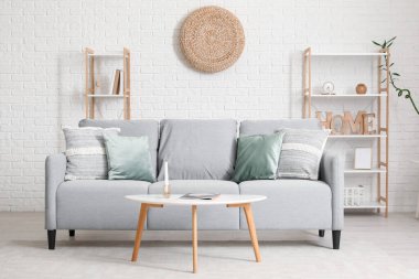 Gri kanepe, masa ve raf üniteleriyle modern oturma odasının içinde.