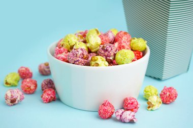 Mavi arka planda tatlı renkli patlamış mısır kasesi