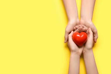 Sarı arka planda kırmızı kalpli kadın ve çocuğun elleri