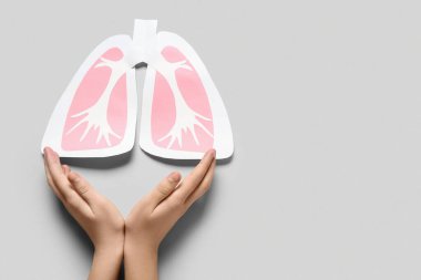 Gri arka planda kağıt ciğerli kadın elleri