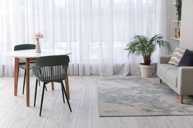 Masası, sandalyeleri, kanepesi, çiçekleri ve raf ünitesi olan geniş bir oturma odası.