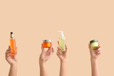 Kavanozlu ve şişeli kadın elleri bej arka planda farklı kozmetik ürünler